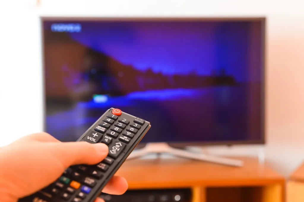 Hand pointing a remote control at a TV